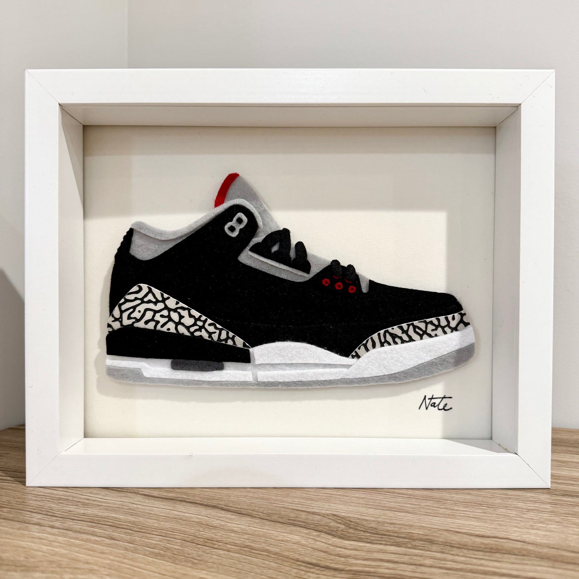 Handmade felt sneaker art with black elephant print accents, framed