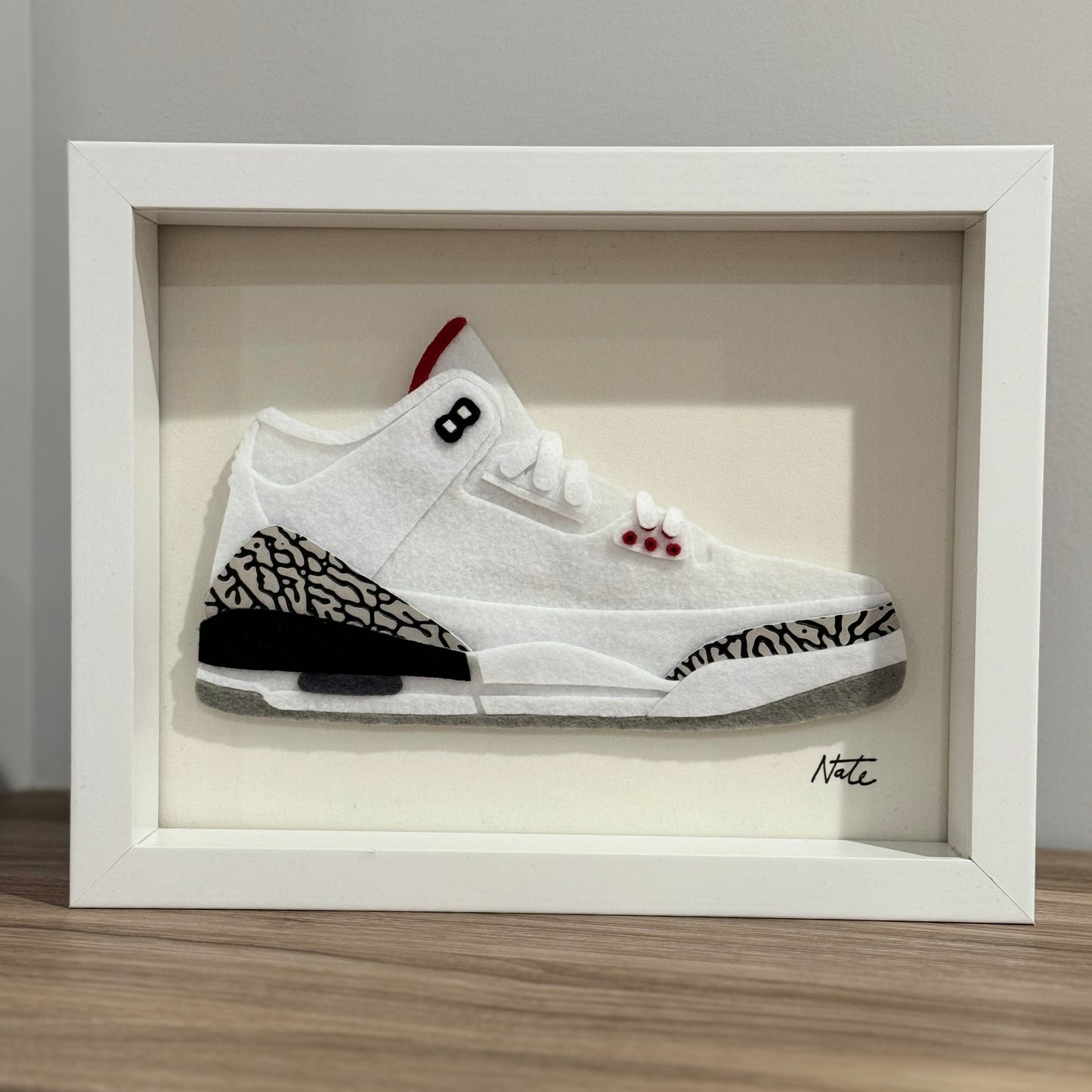 Handmade felt sneaker art with white elephant print accents, framed