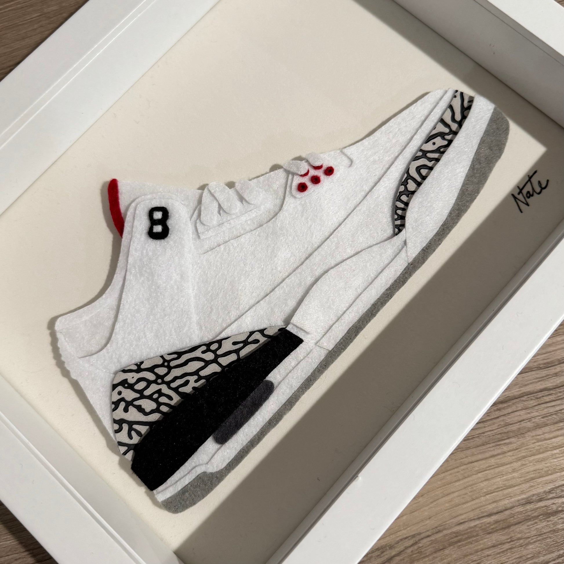 Handmade felt sneaker art with white elephant print accents, framed