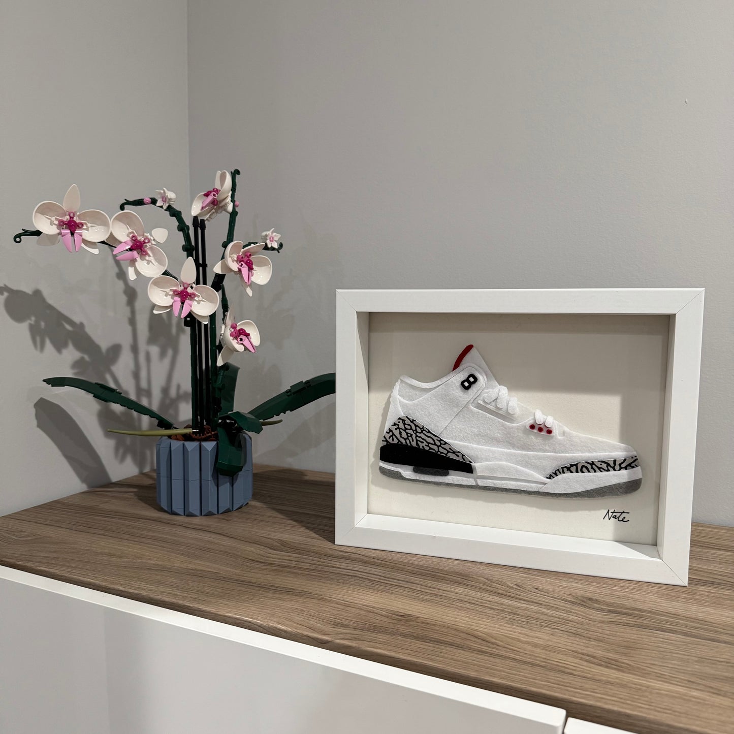 Handmade felt sneaker art with white elephant print accents, framed