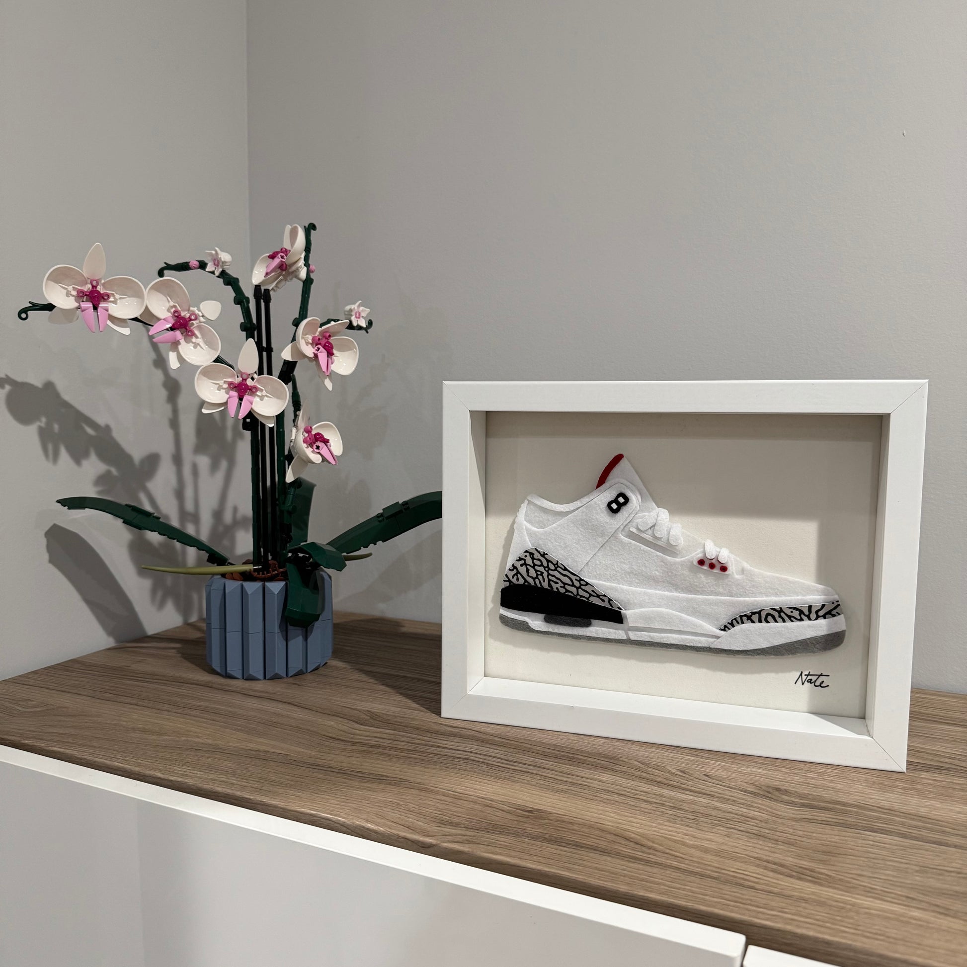 Handmade felt sneaker art with white elephant print accents, framed