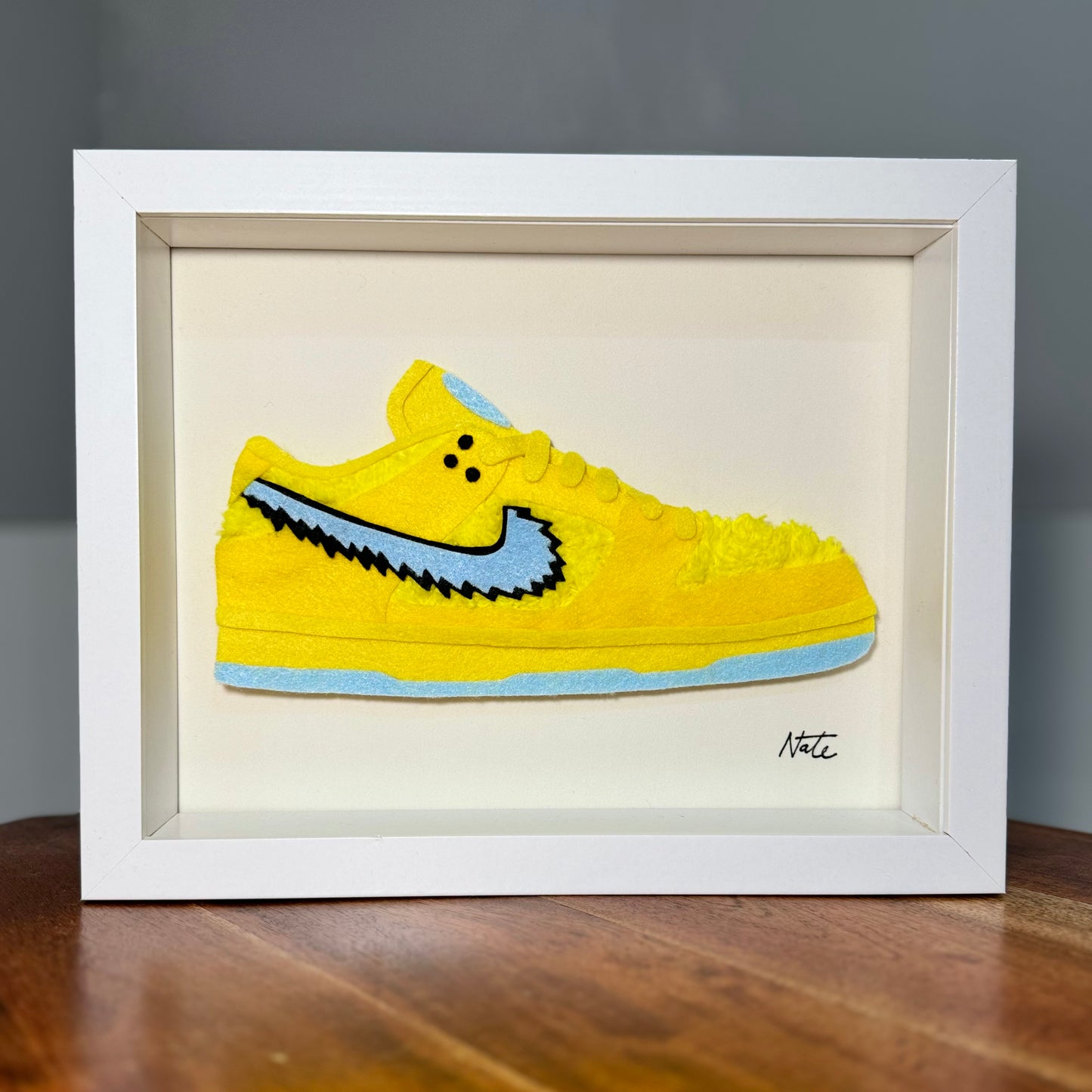 Handmade felt sneaker art with yellow bear faux fur accents, framed